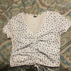 white crop top with blue flowers and a drawstring in the front